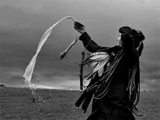 Женщина, проходящая обряд посвящения в шаманы неподалеку от Улан-Батора, приносит в дар духам молоко. Фото Кэролин Дрейк.